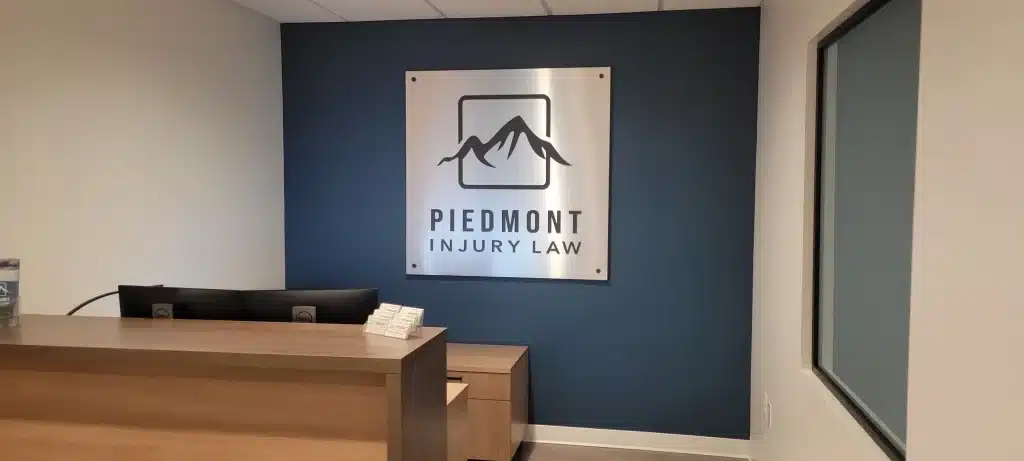 Reception logo sign on accent wall for Piedmont Injury Law in Kennesaw, GA, by High Stakes Creative