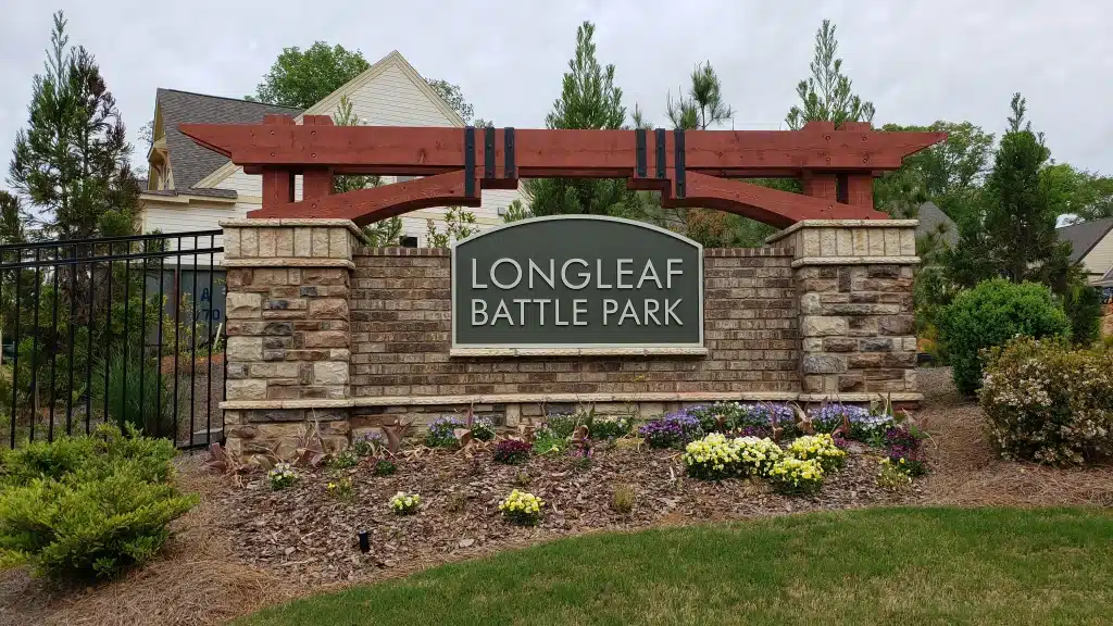 Longleaf Battle Park entrance sign with stone base and wooden arch, showcasing custom signage for community branding.