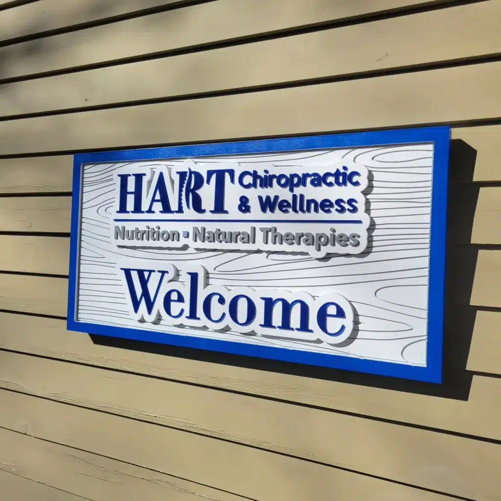 Raised blue and white HART Chiropractic & Wellness sign on a tan building.