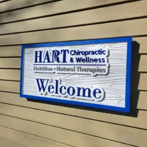 Raised blue and white HART Chiropractic & Wellness sign on a tan building.