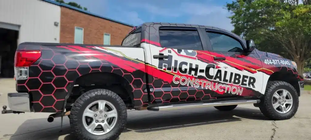 Pickup truck with a bold, colorful wrap advertising High-Caliber Construction.