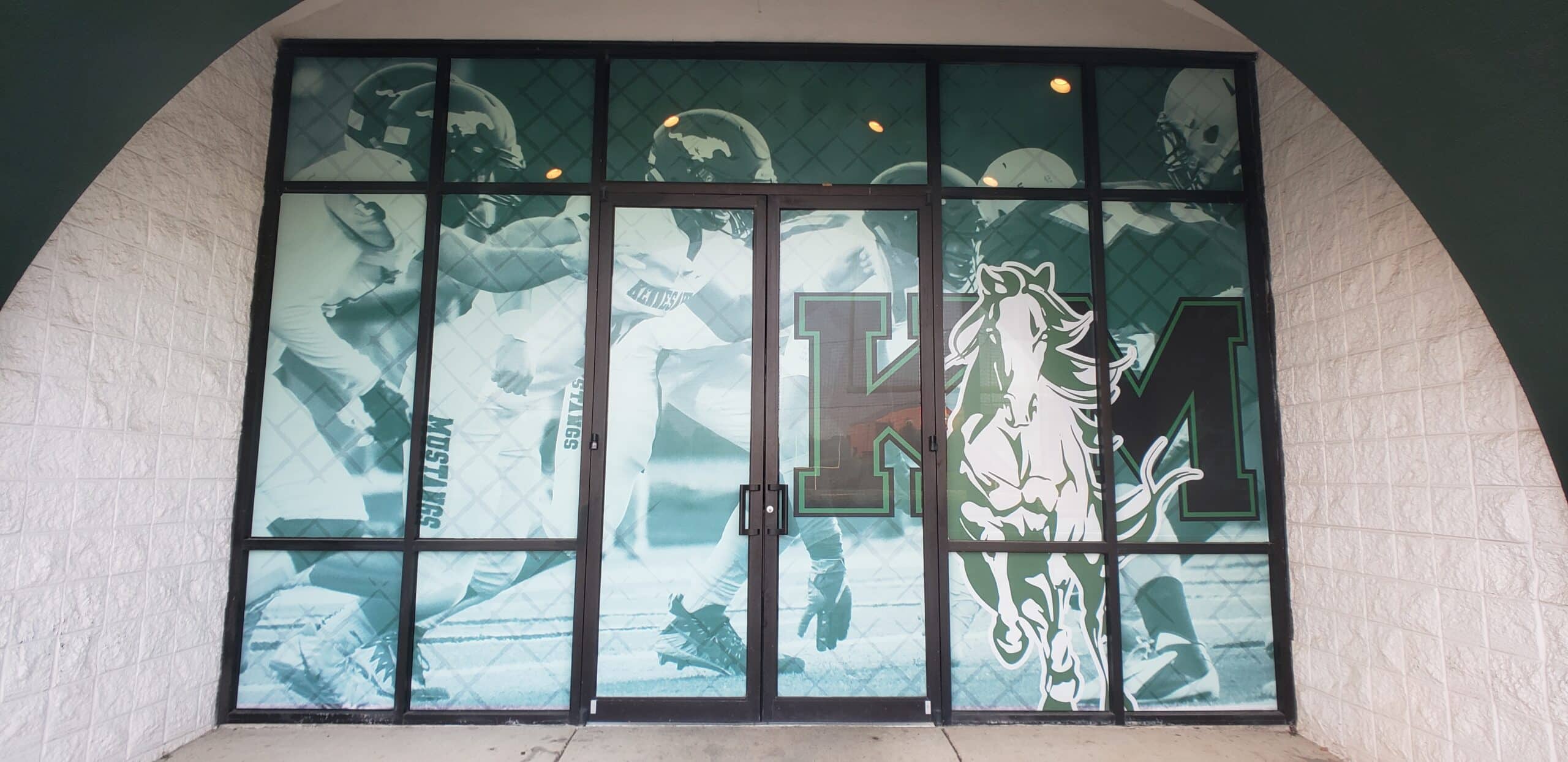 Perforated/printed window graphics with football photos and KM mustang logo at arched scho, Kennesaw Mountain, Kennesaw, GA, by High Stakes Creative
