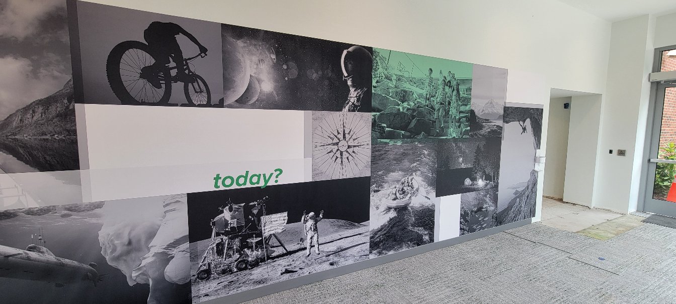 Long black-and-white photo collage corridor mural (landmarks, adventure scenes) with "What, by High Stakes Creative
