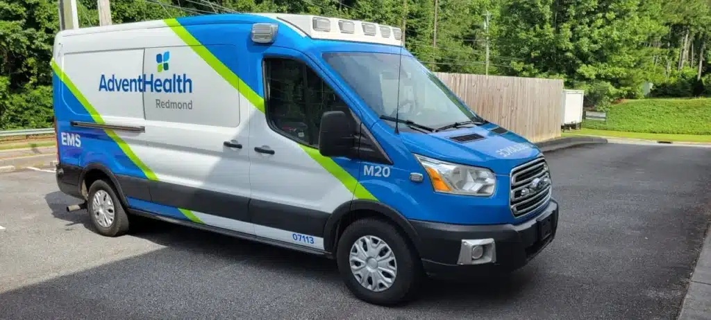 AdventHealth Redmond EMS ambulance, blue and white with green trim, parked outdoors.