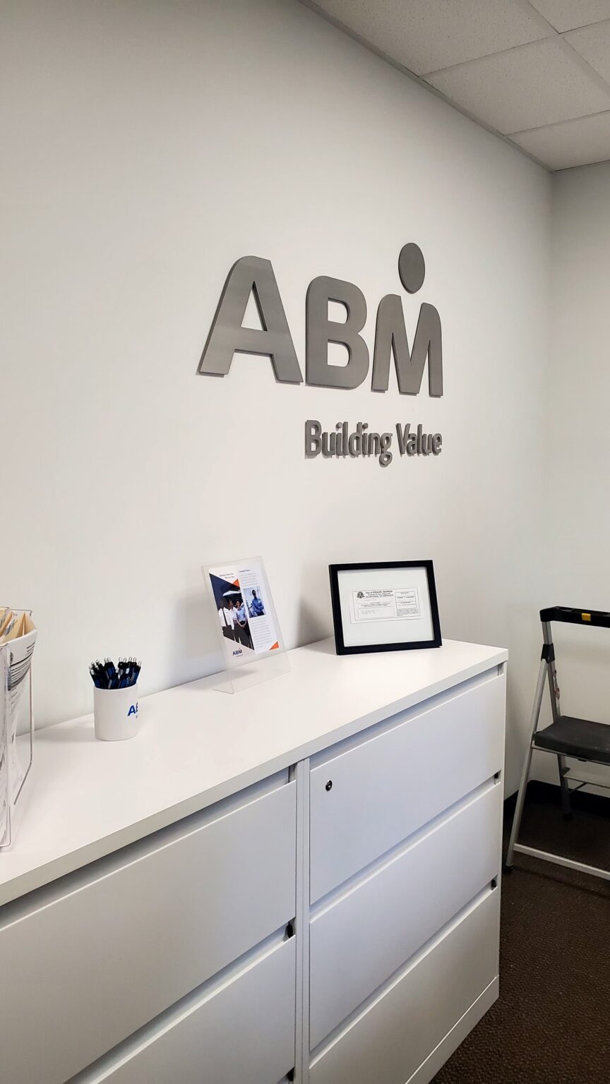 Brushed-metal dimensional logo wall in office lobby, ABM, Pooler, GA, by High Stakes Creative