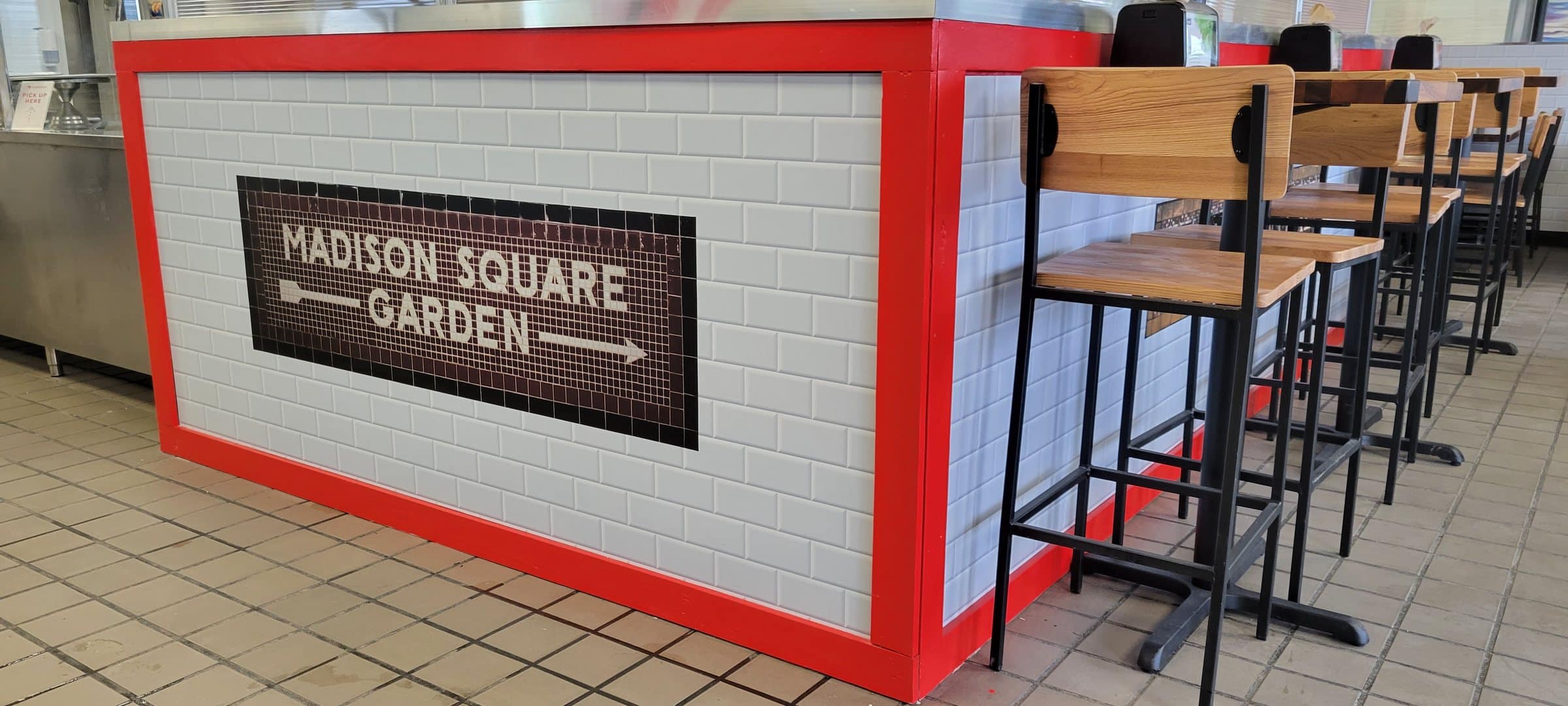 Subway-tile wall wrap with red trim around bar seating, Baby Tommy's Taste of New York, by High Stakes Creative
