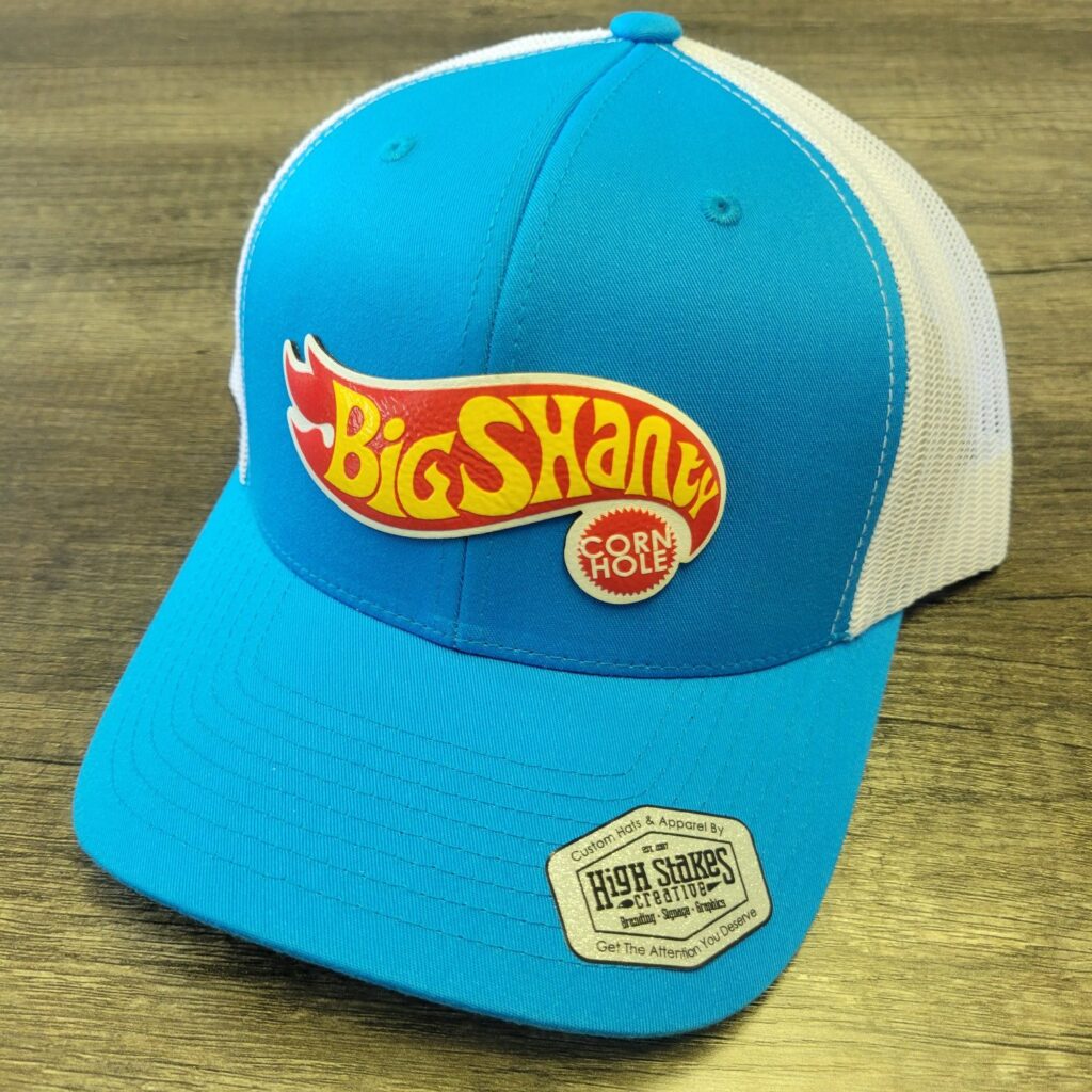 Custom trucker hat with UV-printed logo patch, Big Shanty Cornhole, by High Stakes Creative