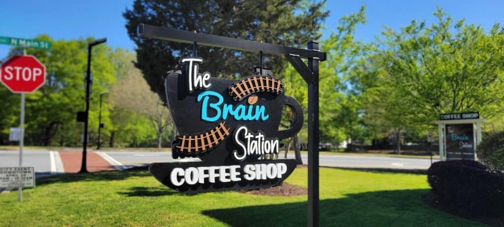 Coffee-cup shaped hanging sign on post, close, The Brain Station Coffee Shop, by High Stakes Creative