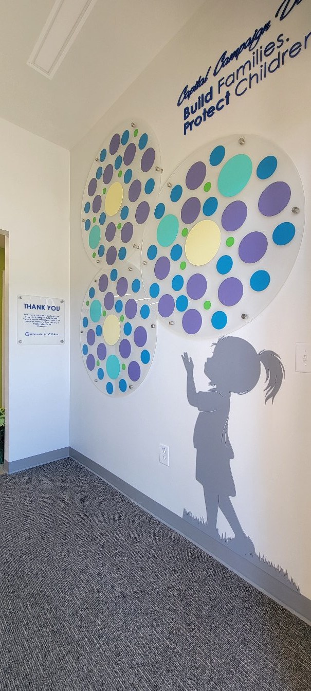 Circle-cluster donor wall with child silhouette, by High Stakes Creative