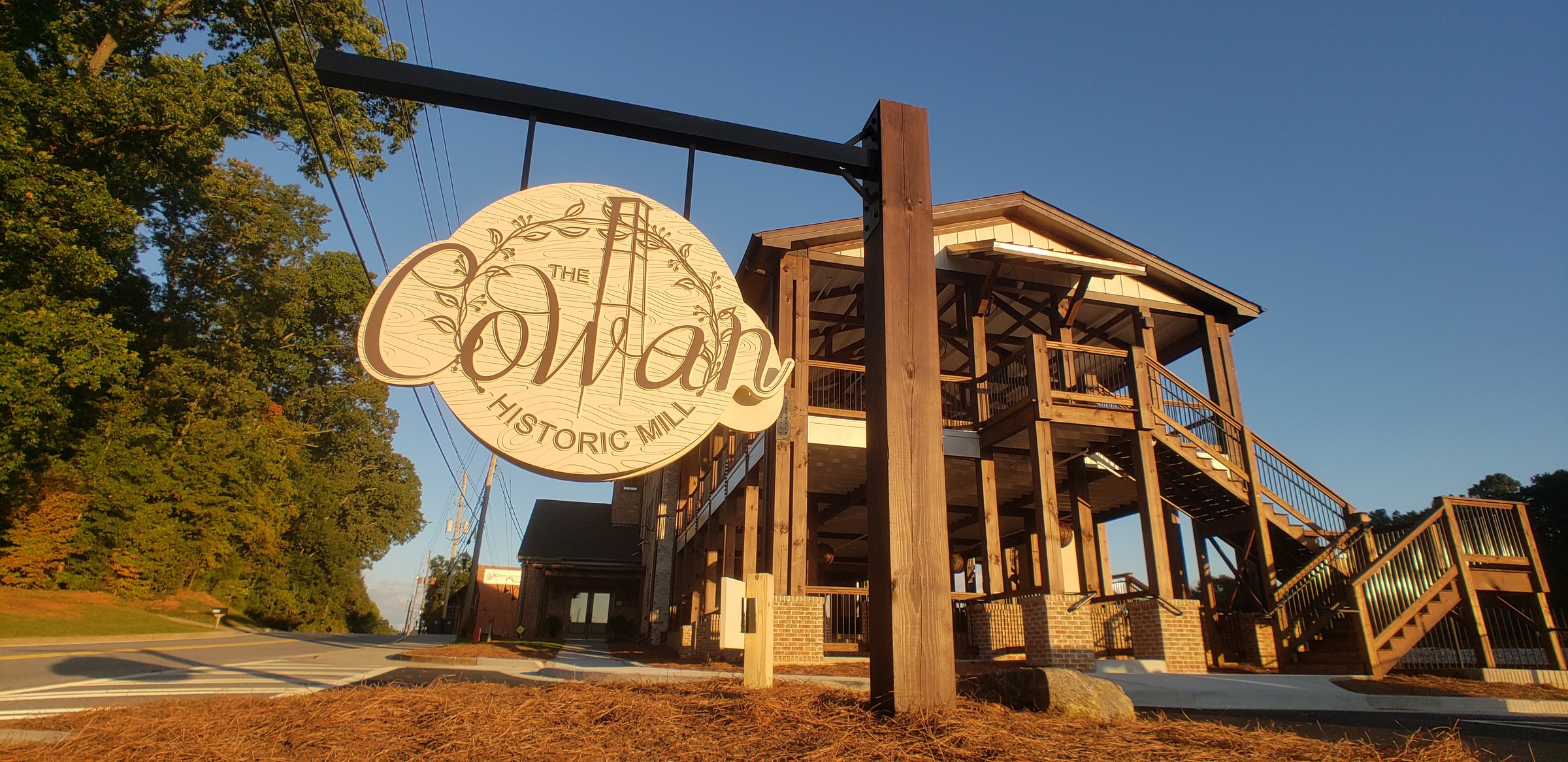 Carved hanging sign against the sky, The Cowan Historic Mill, Acworth, GA, by High Stakes Creative