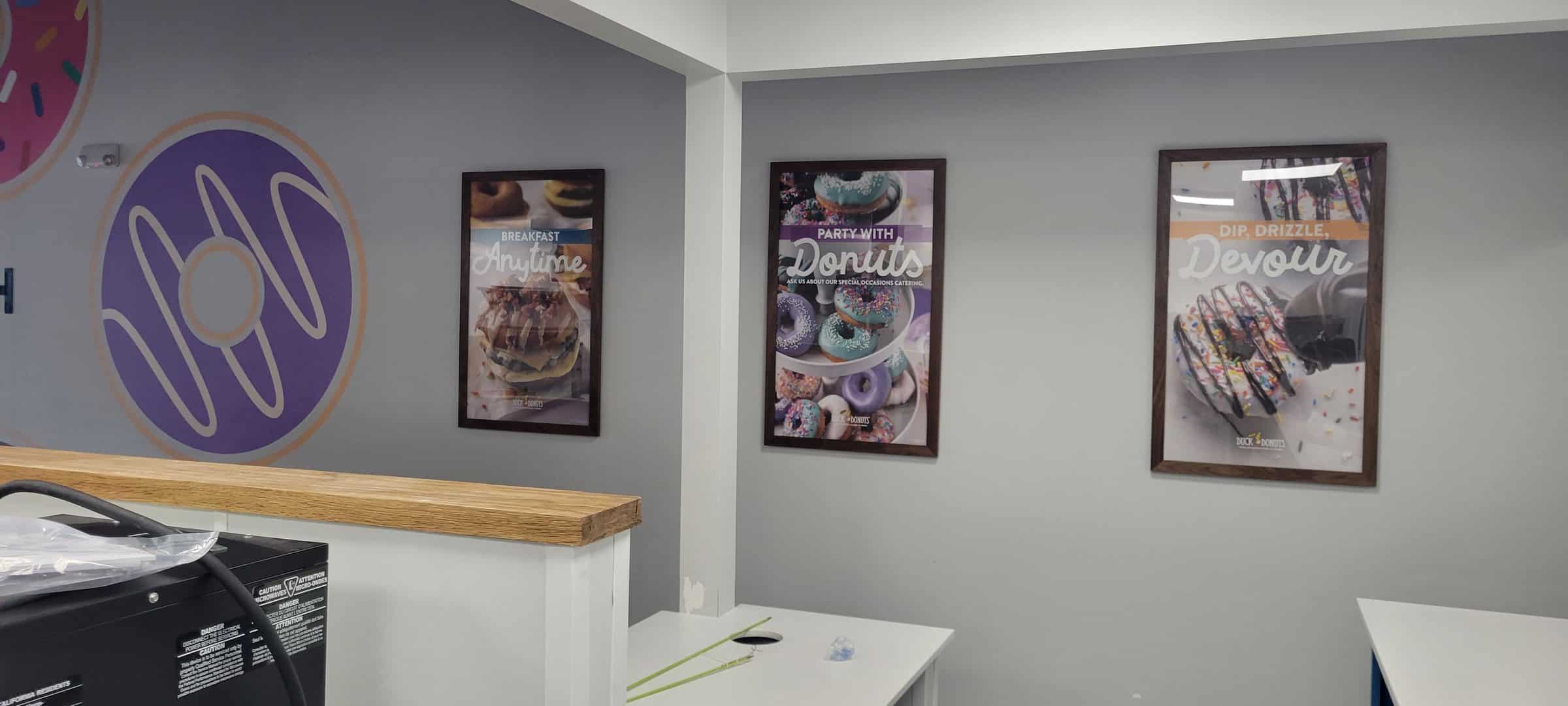 Framed product posters above service counter, Duck Donuts, Acworth, GA, by High Stakes Creative