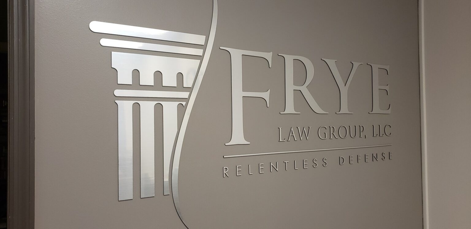 Brushed-metal dimensional logo with column icon and "Relentless Defense" tagline on gray r, Frye Law Group, by High Stakes Creative
