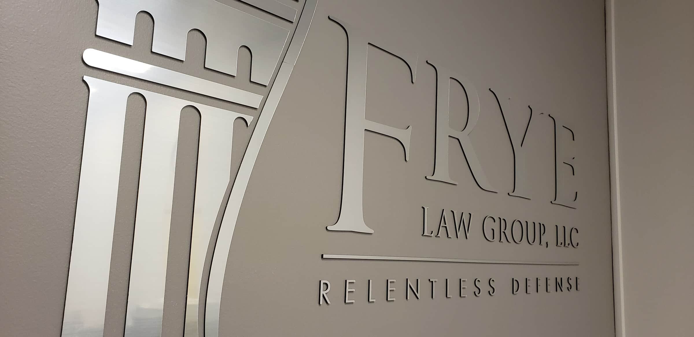 Brushed-metal dimensional logo with column icon and "Relentless Defense" tagline on gray r, Frye Law Group, by High Stakes Creative