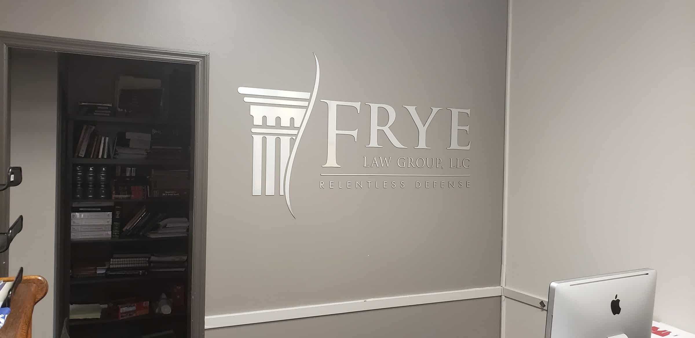 Brushed-metal dimensional logo with column icon and "Relentless Defense" tagline on gray r, Frye Law Group, by High Stakes Creative