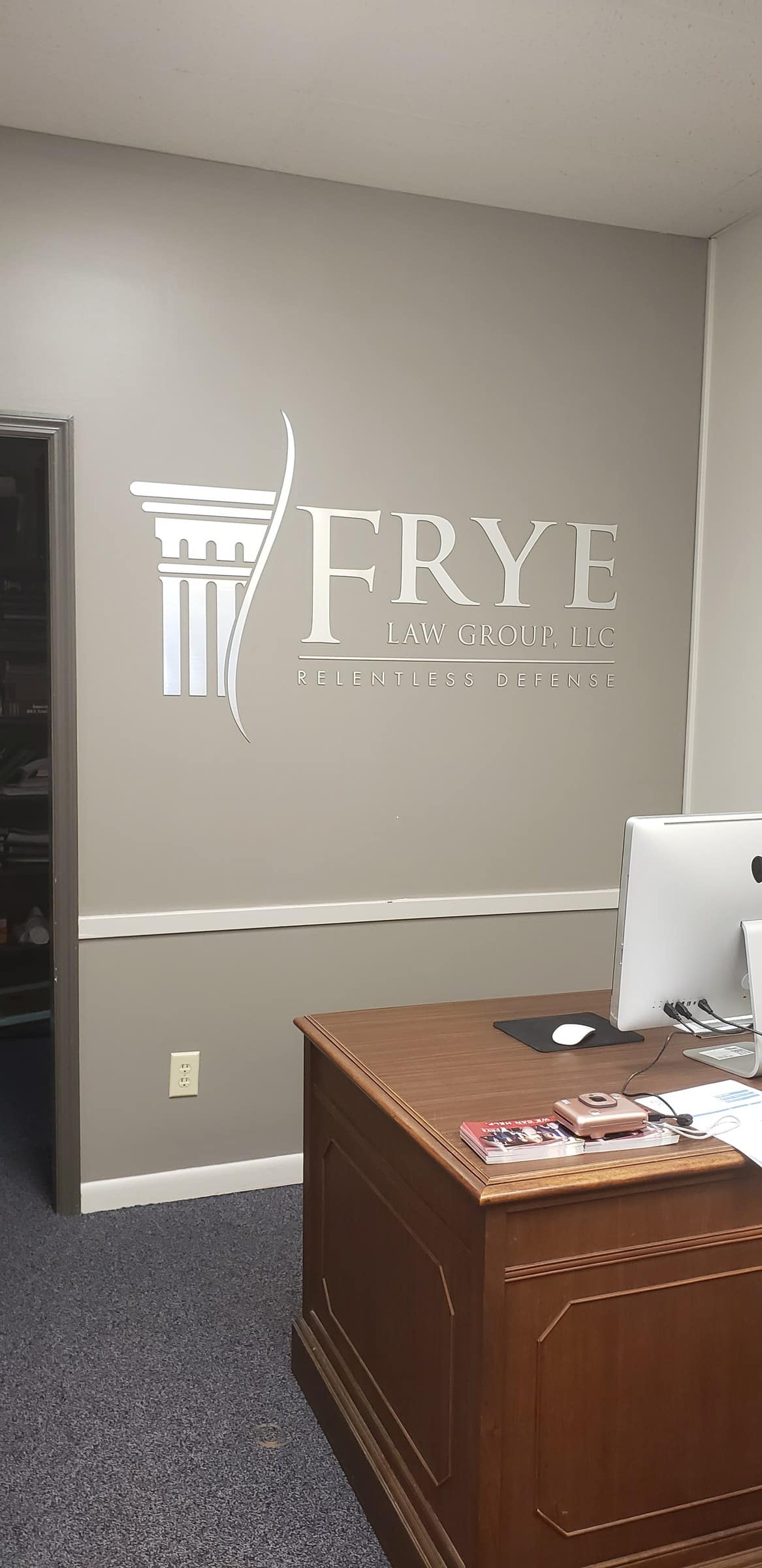 Brushed-metal dimensional logo with column icon and "Relentless Defense" tagline on gray r, Frye Law Group, by High Stakes Creative