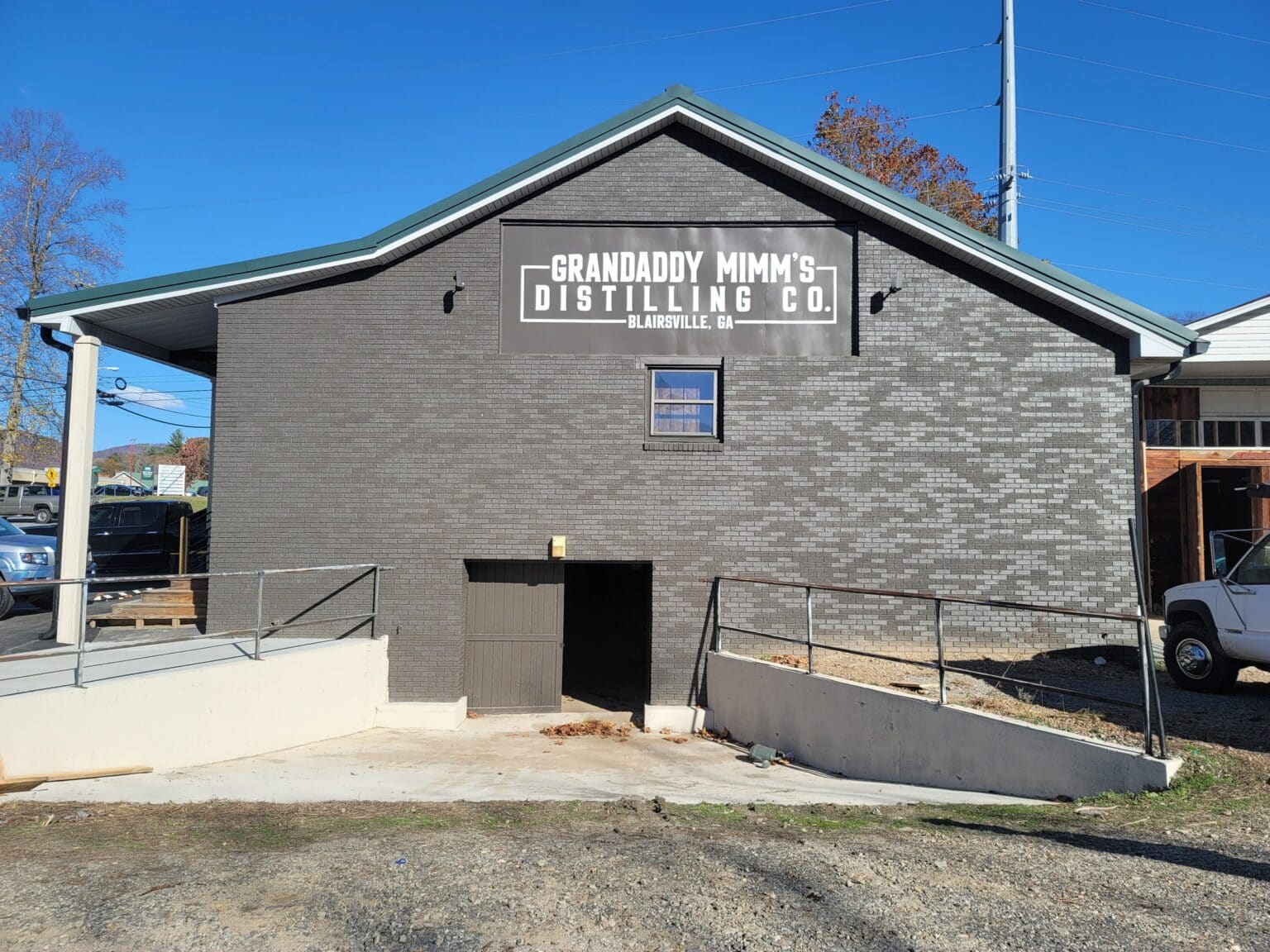 Large exterior wall sign on gable of gray brick distillery building, Grandaddy Mimm's Distilling Co., Blairsville, GA, by High Stakes Creative