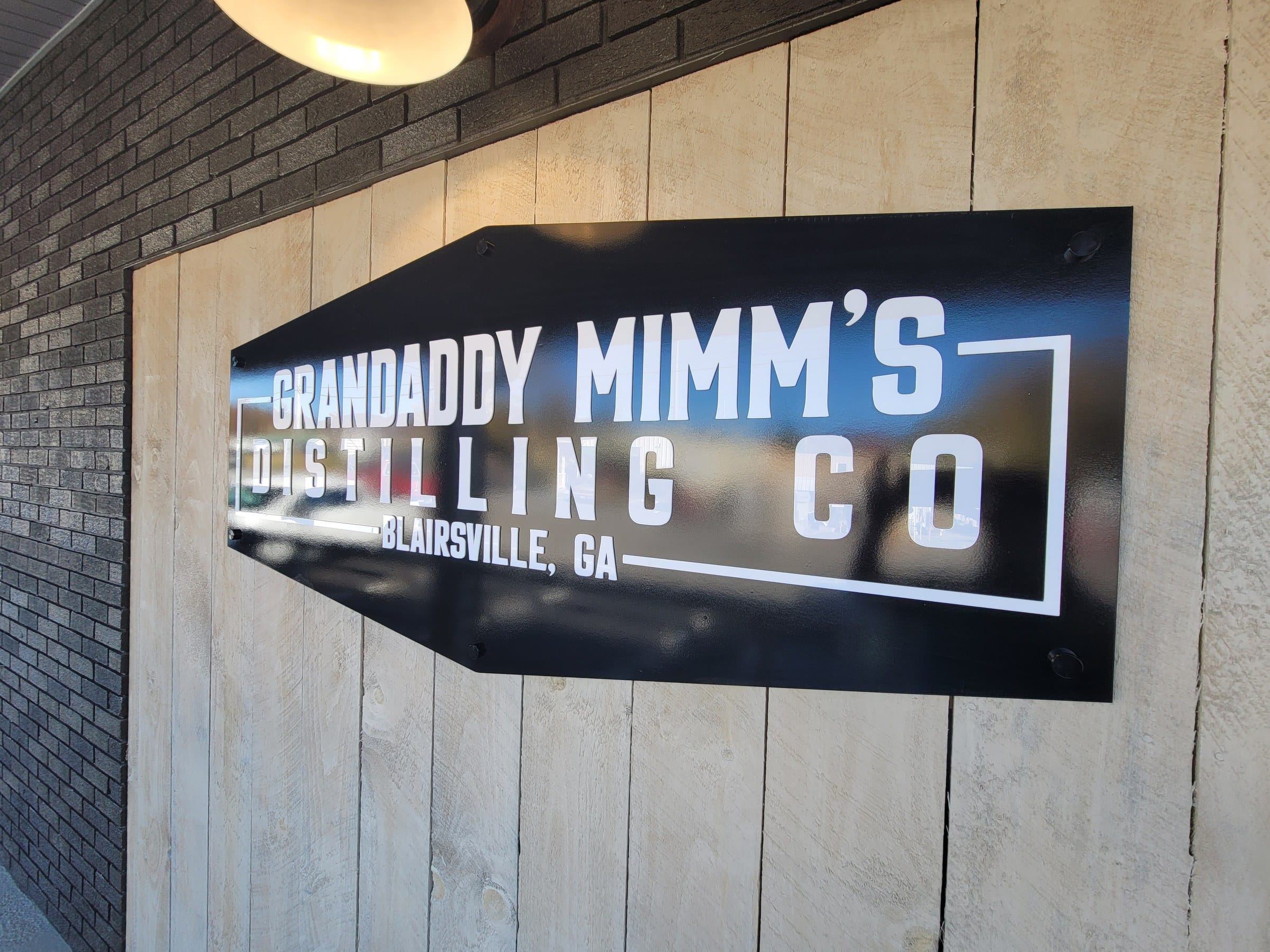 Angled view of hexagonal panel sign on plank wall, Grandaddy Mimm's Distilling Co., Blairsville, GA, by High Stakes Creative