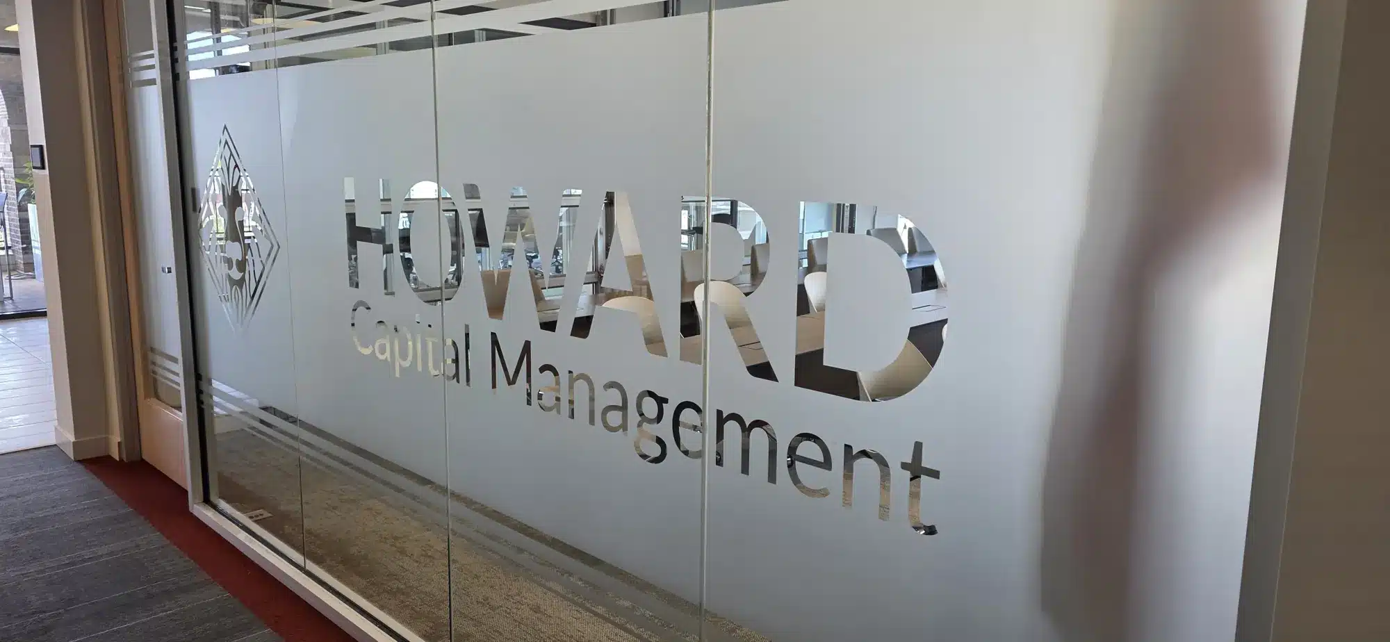 Frosted glass office branding with the Howard Capital Management logo, installed by High Stakes Creative