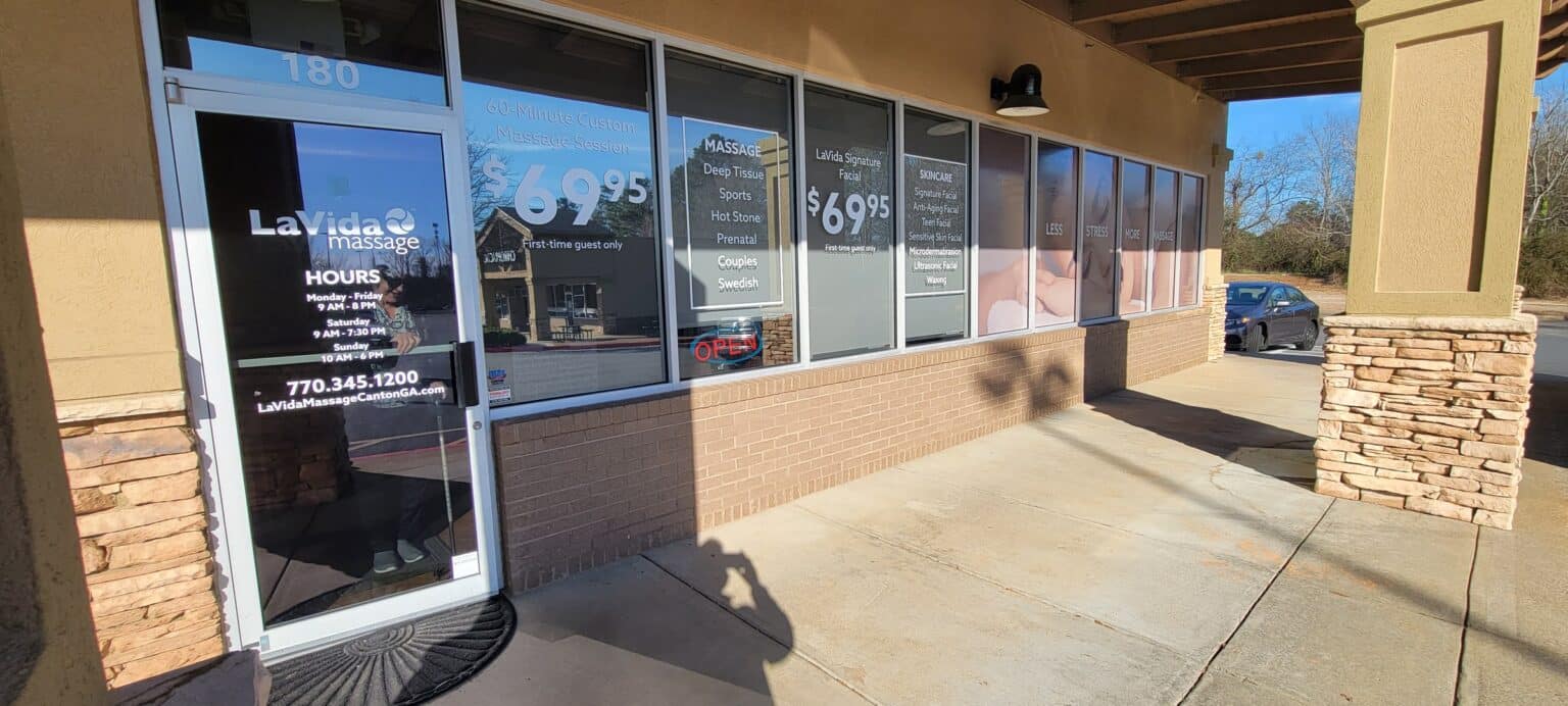 Storefront window graphics: door hours/logo decal, price window and full-height lifestyle , LaVida Massage, Canton, GA, by High Stakes Creative