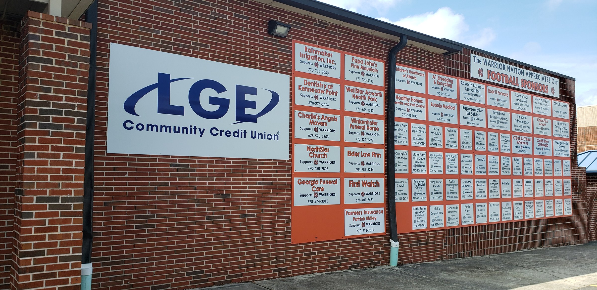 Wider view: LGE sign plus wall of sponsor panels, LGE Community Credit Union, by High Stakes Creative