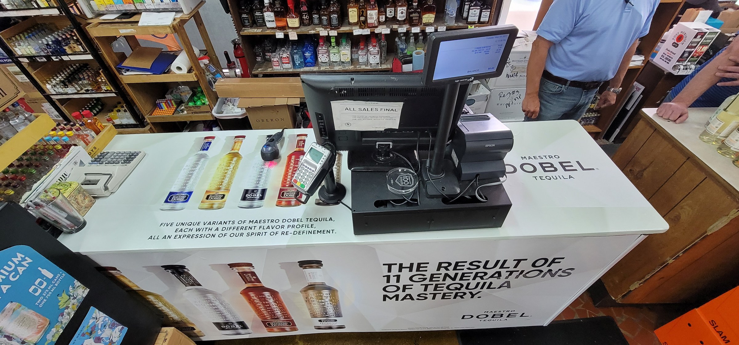 Printed wrap on liquor-store checkout counters showing Maestro Dobel bottles and tagline, Maestro Dobel Tequila, by High Stakes Creative