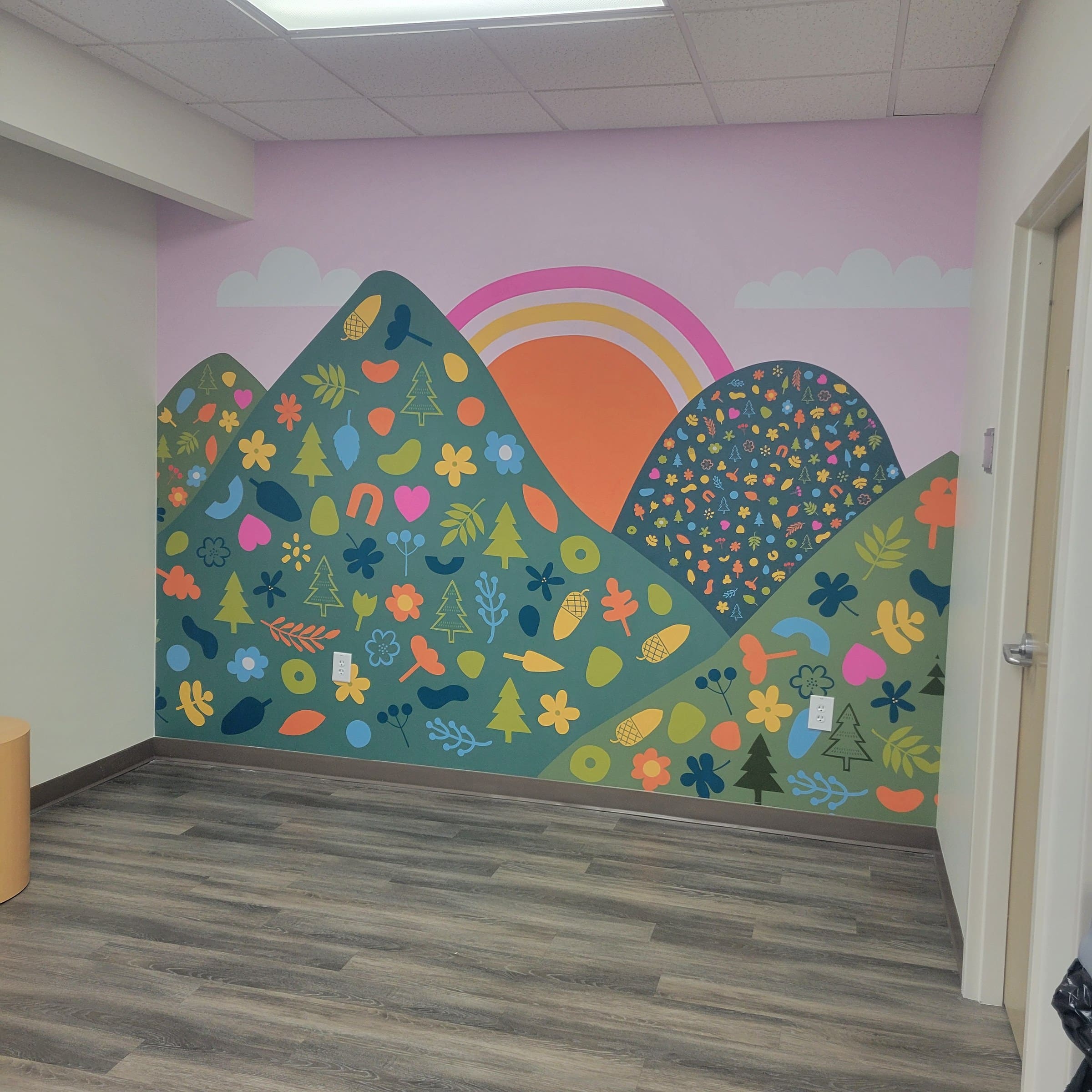 Illustrated mountain/flower/sun wall murals in office rooms and a framed lobby wall (day a, by High Stakes Creative