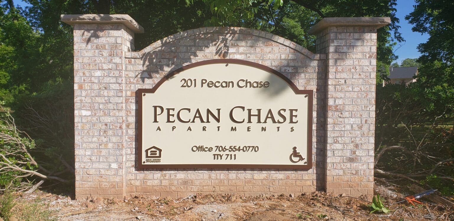 Brick monument with carved Pecan Chase Apartments panel, 201 Pecan Chase, Pecan Chase Apartments, by High Stakes Creative
