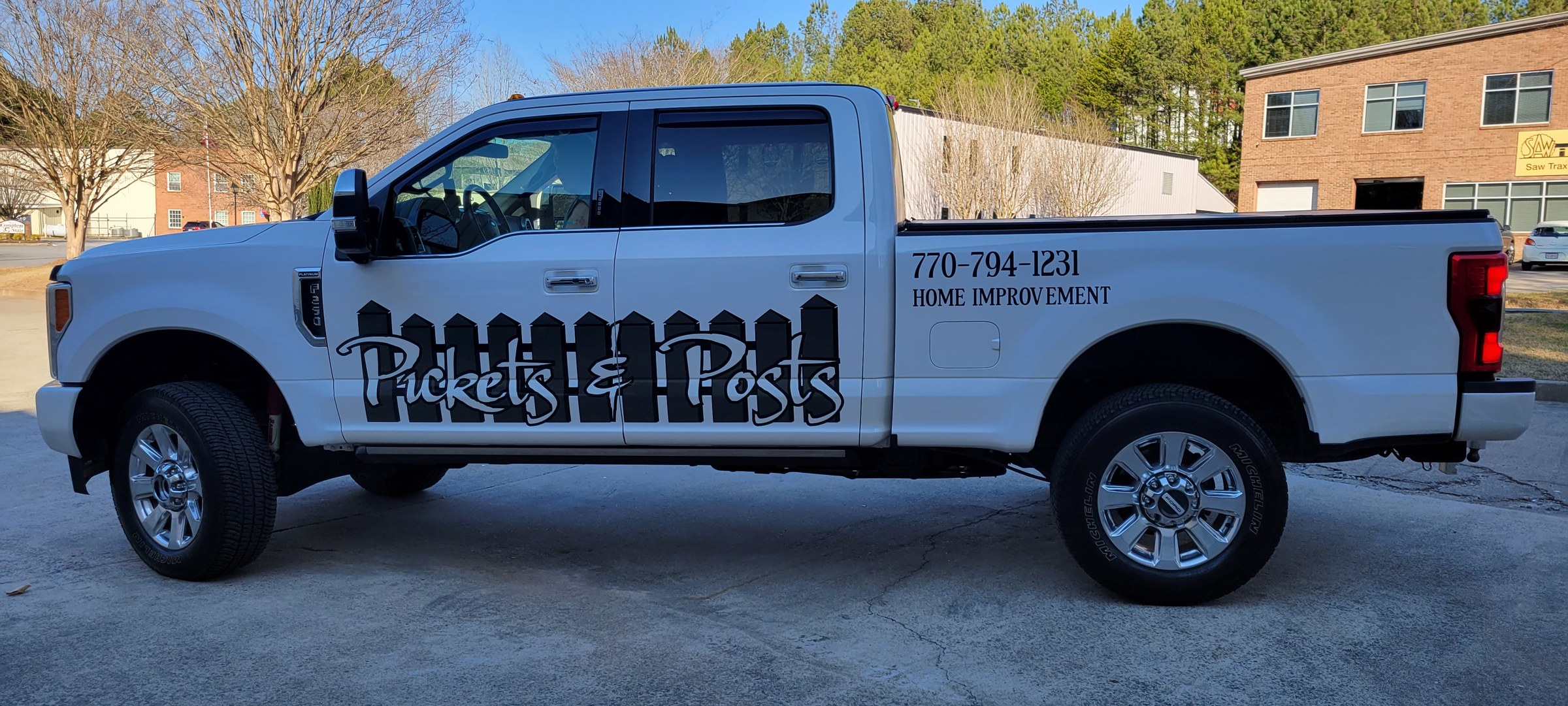 Black fence-silhouette logo and phone graphics on a white Ford Super Duty, Pickets & Posts, by High Stakes Creative