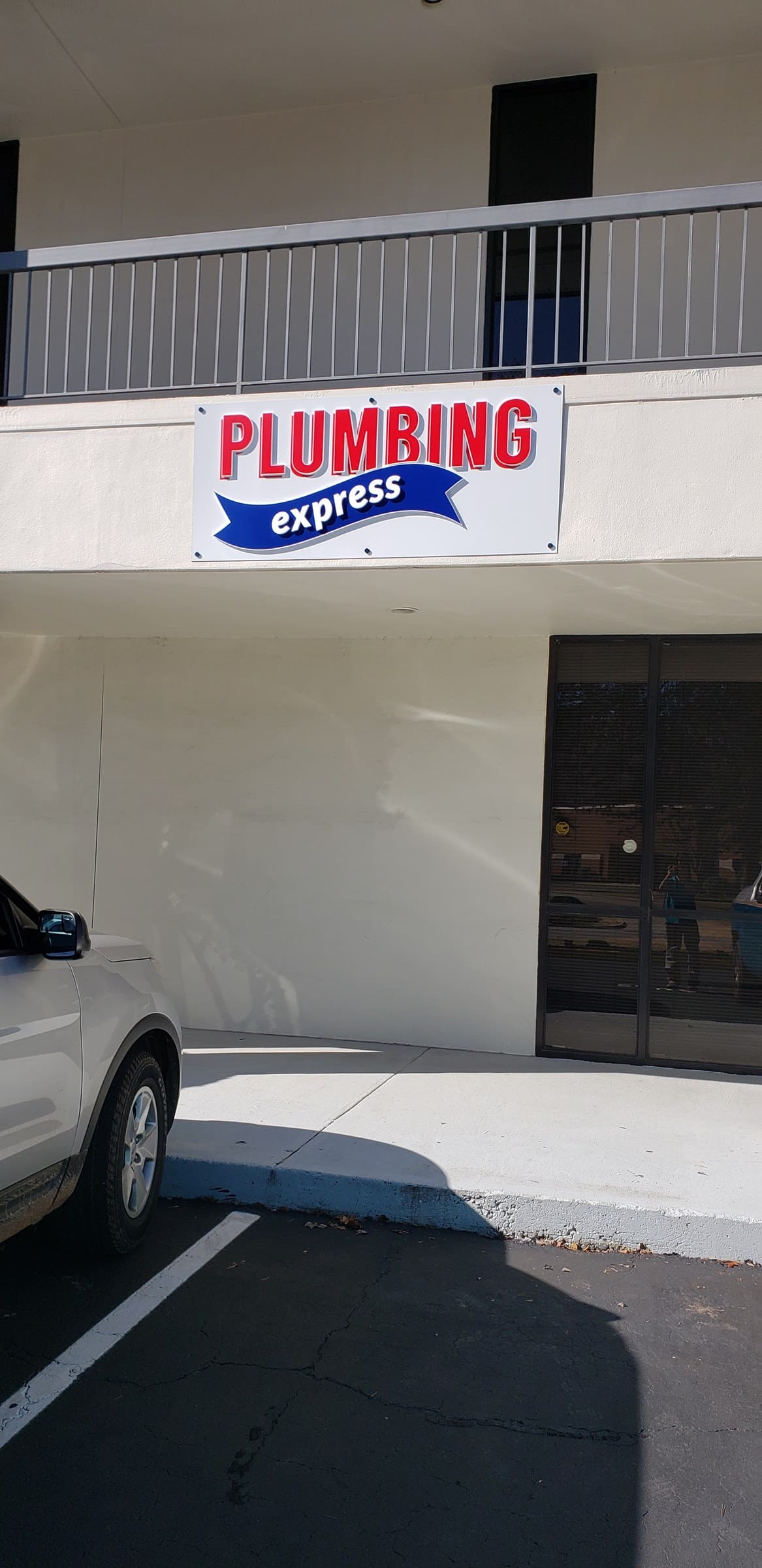 Plumbing Express logo sign on building facade over entry, Plumbing Express, by High Stakes Creative