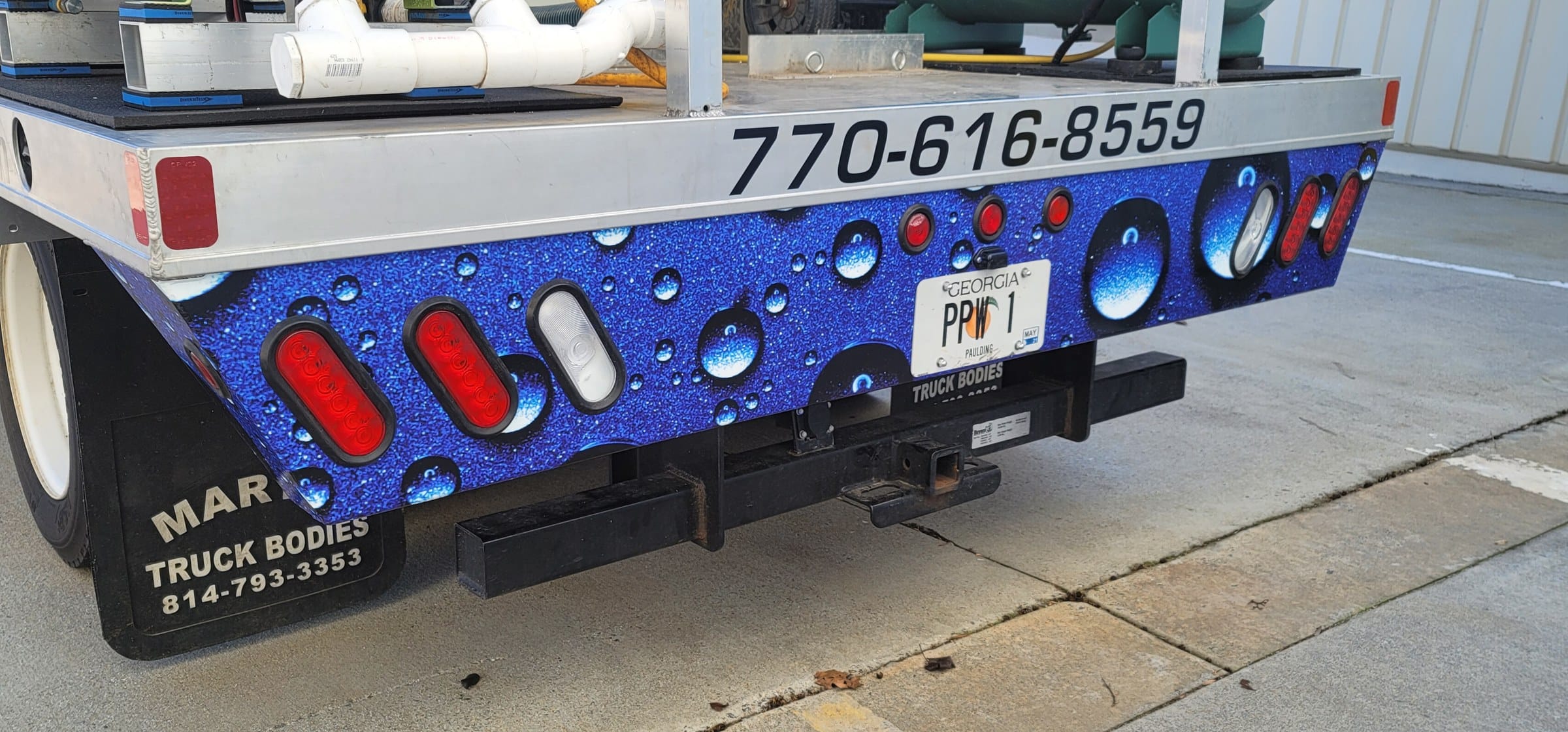 Water-droplet graphics on the rear of a flatbed wash truck with phone number, Precision Pressure Washing, by High Stakes Creative
