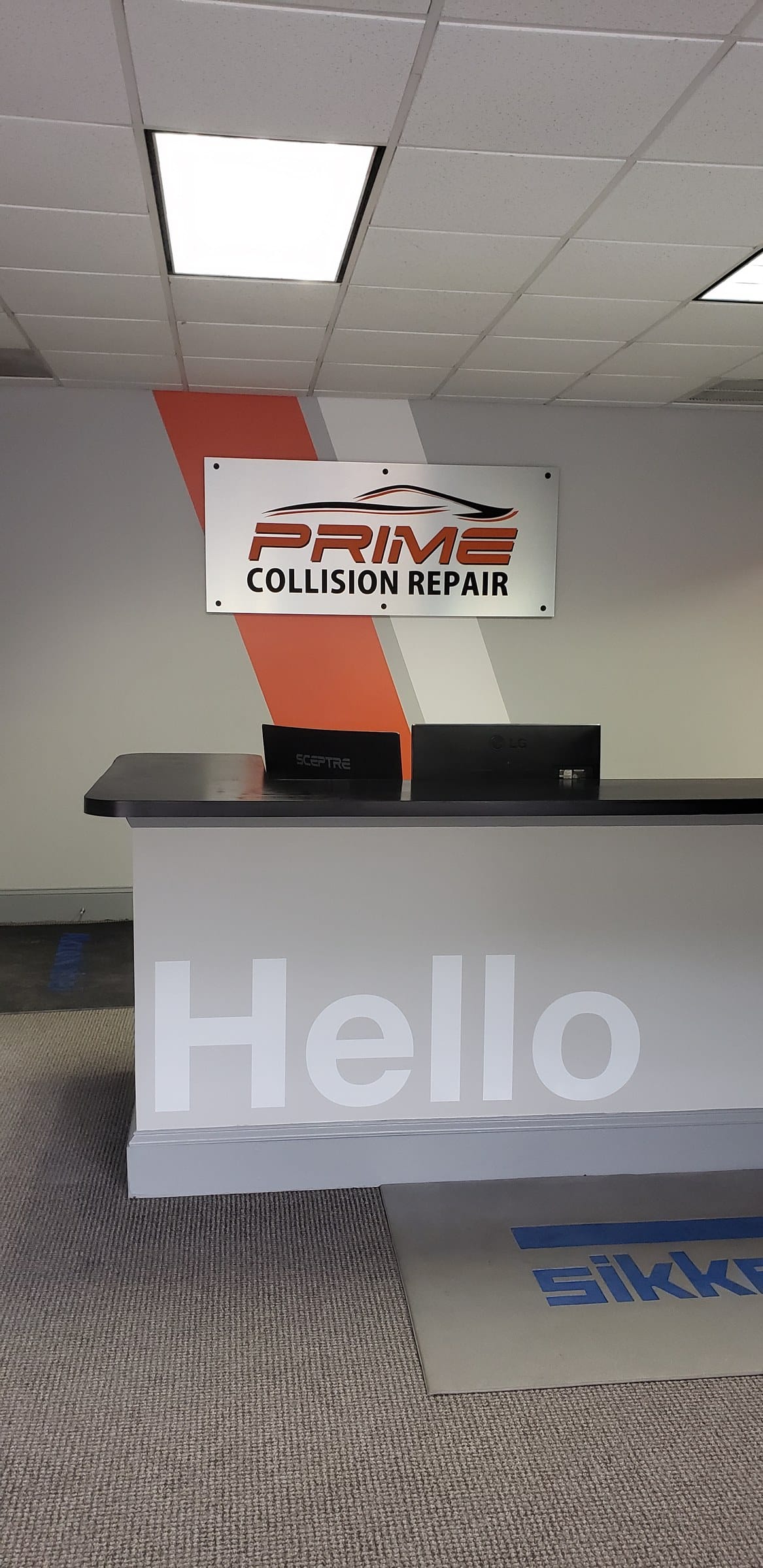 Reception area: logo panel on orange/white striped accent wall and "Hello" graphic on fron, Prime Collision Repair, by High Stakes Creative