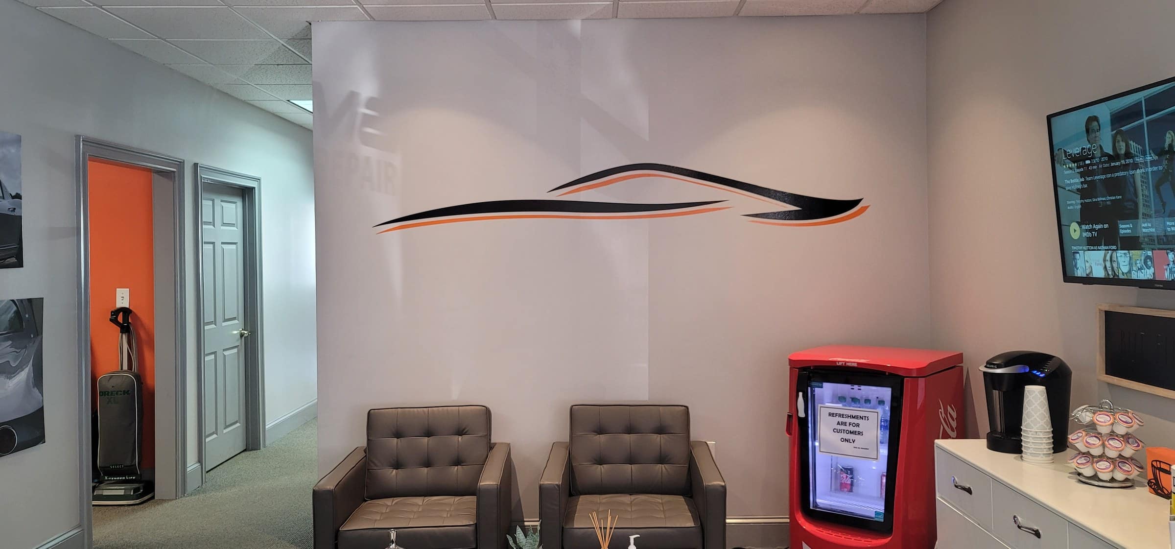 Lobby wall graphic of car silhouette in orange and black, Prime Collision Repair, by High Stakes Creative