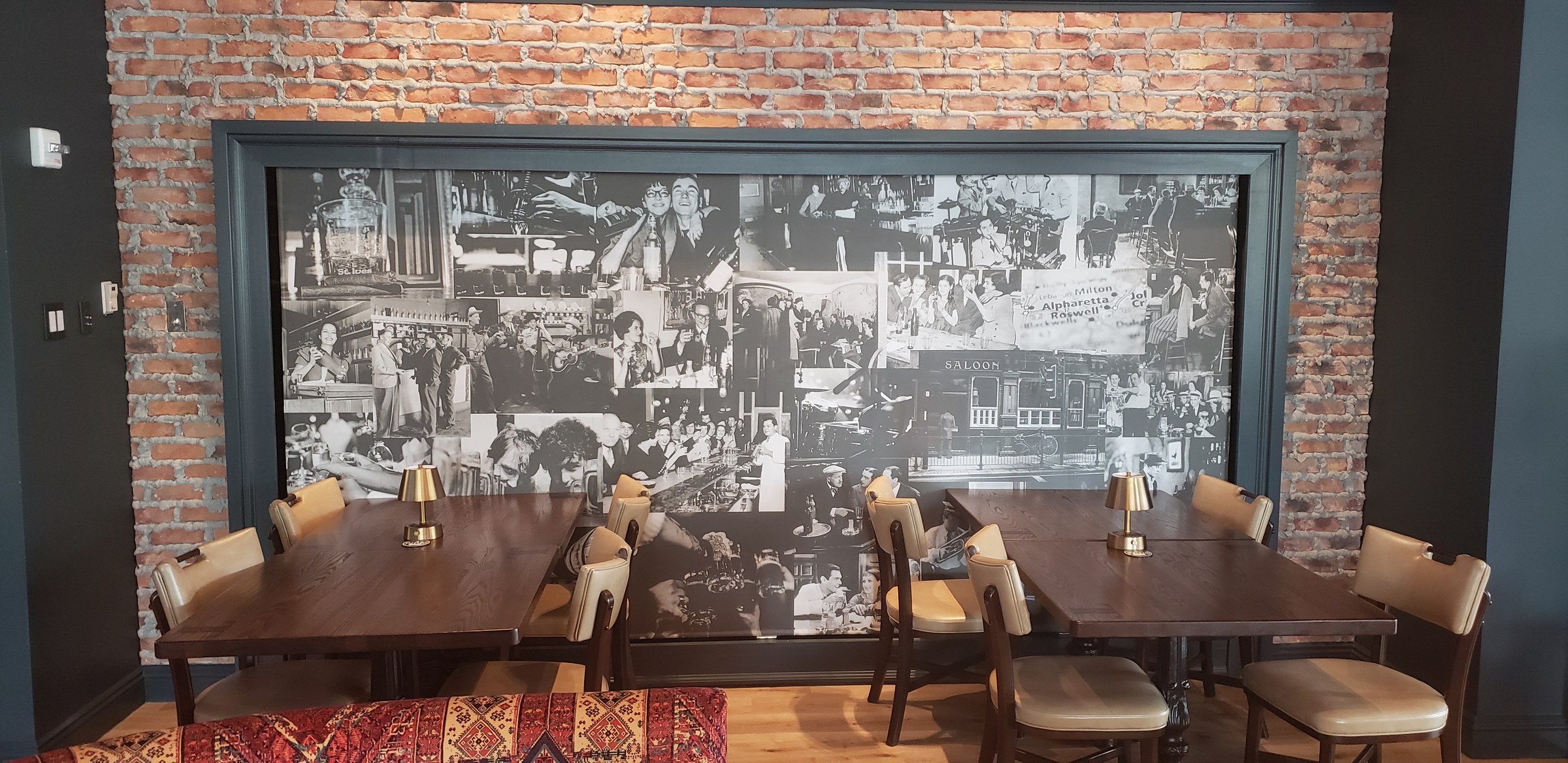 Framed black-and-white vintage bar/saloon photo collage mural on brick wall above dining t, by High Stakes Creative