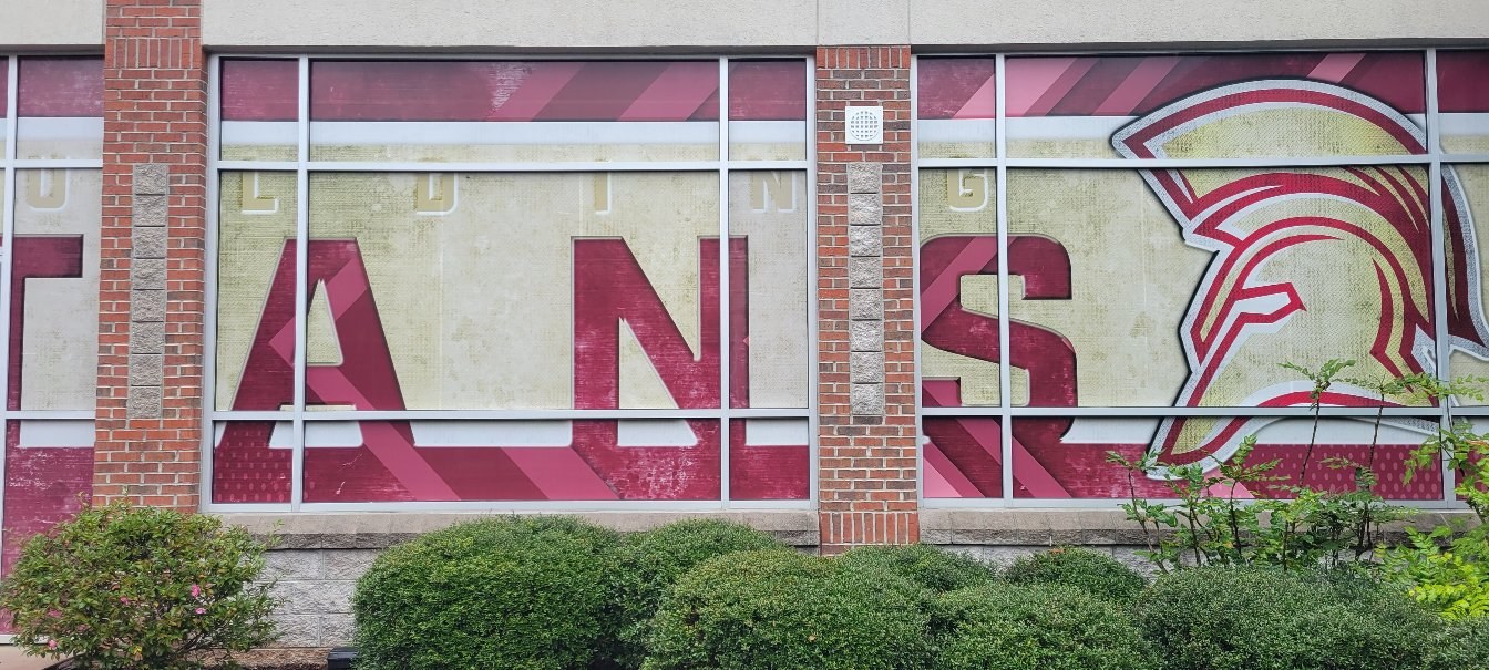 Large SPARTANS lettering and Spartan helmet graphics across school building windows, Spartans, by High Stakes Creative