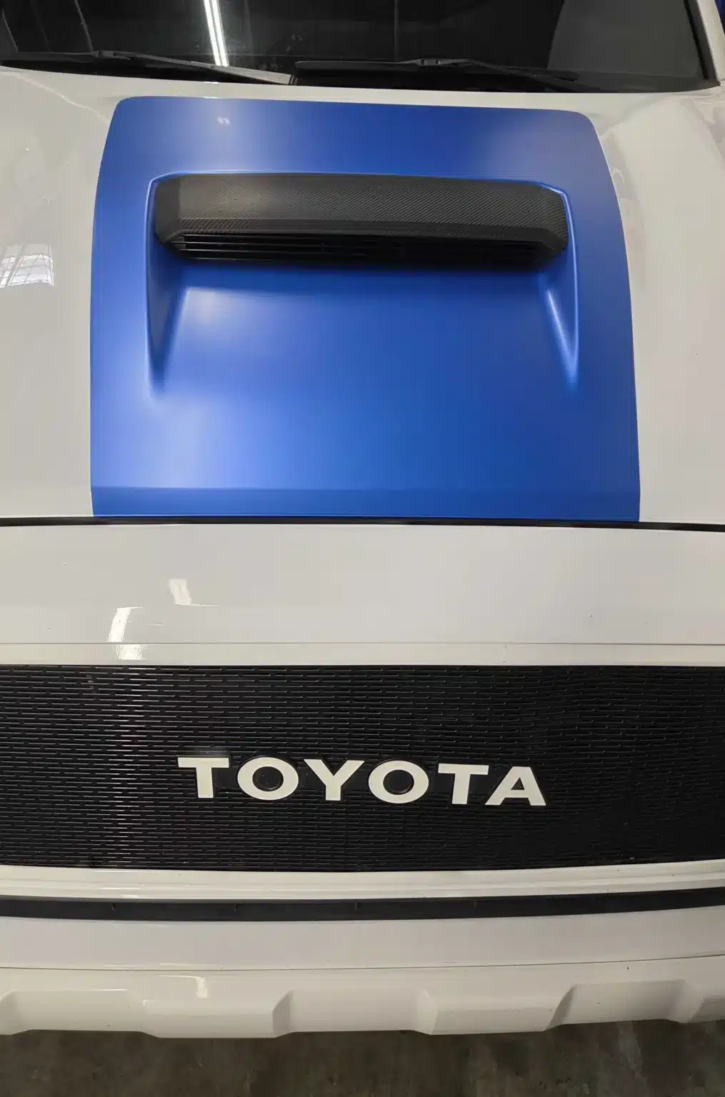 Matte blue hood wrap on a white Toyota pickup, by High Stakes Creative