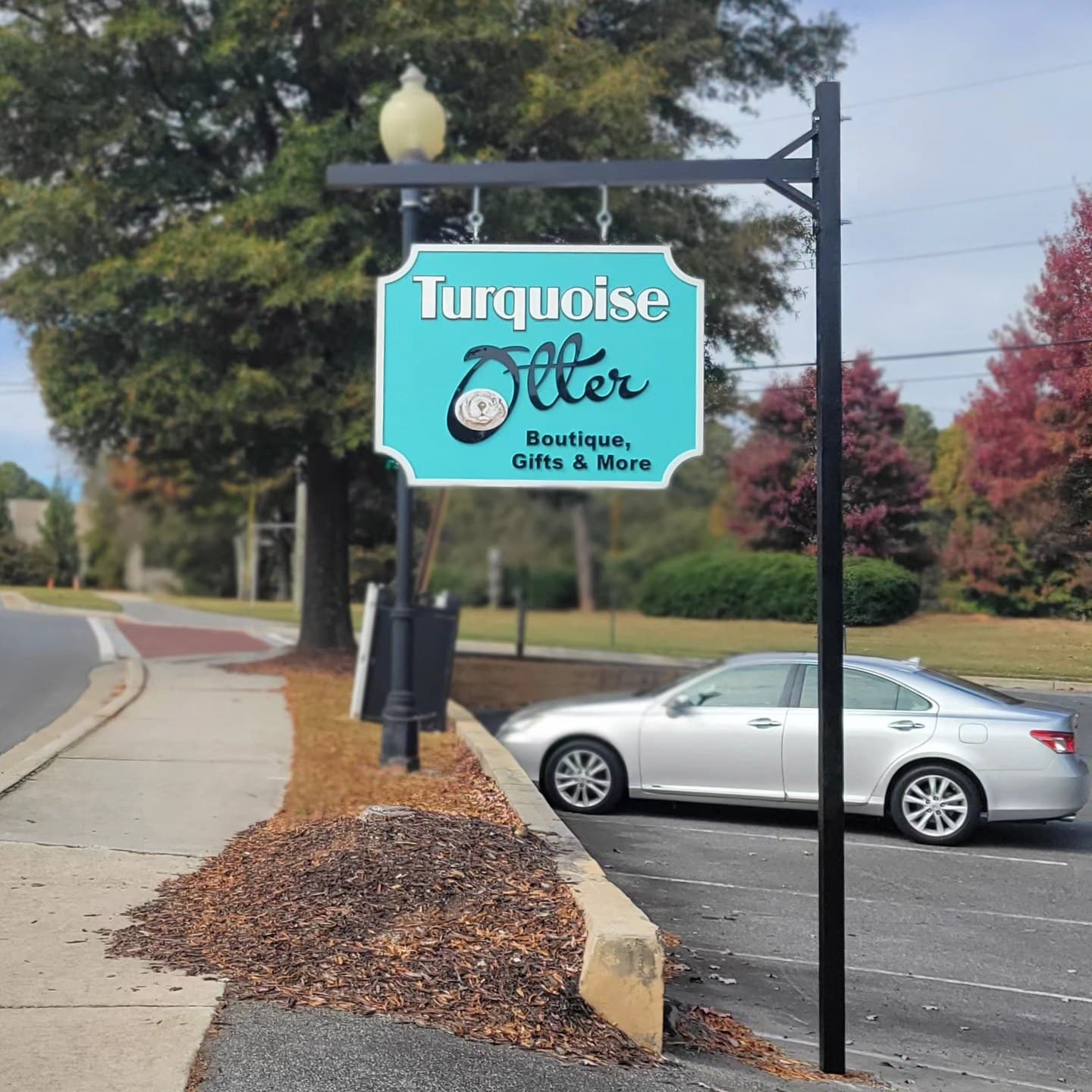 Hanging sign on black post: Turquoise Otter Boutique, Gifts & More, Turquoise Otter, by High Stakes Creative