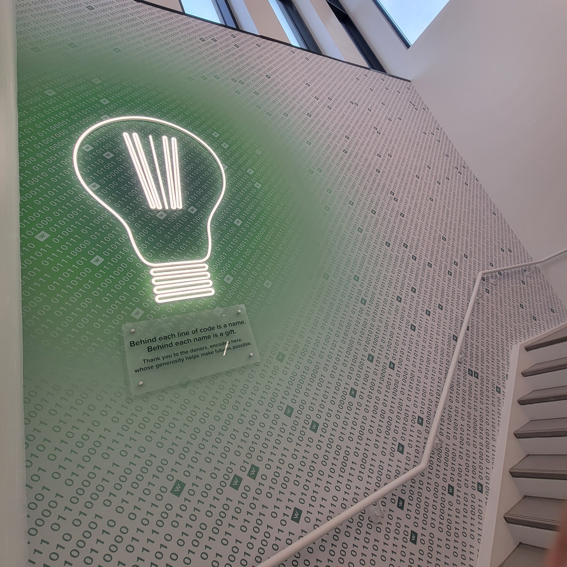 Lightbulb and binary-code mural on stairwell wall, Westminster, by High Stakes Creative